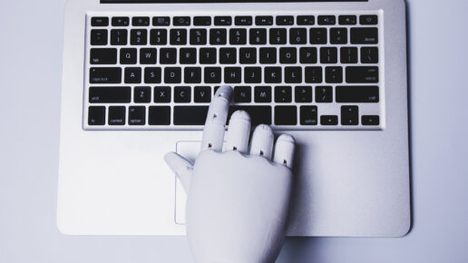 robotic hand using laptop (concept of AI replacing white collar worker)